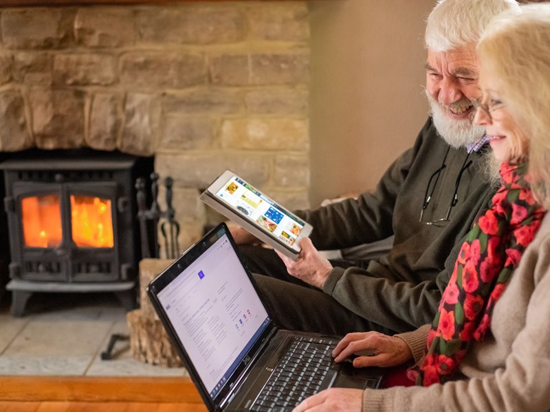 man and woman sat using a phone and laptop
